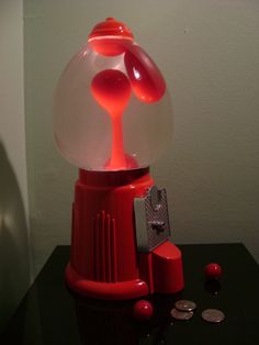 a red gummy machine sitting on top of a black table next to a coin