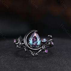 a ring with an amethorate and purple stones in it on a black surface