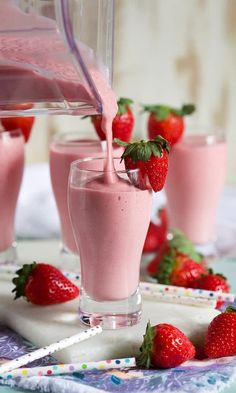 strawberry milk being poured into a glass with strawberries