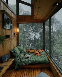 a bed sitting inside of a wooden room next to a window filled with lots of windows