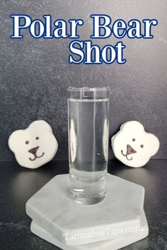 a polar bear shot glass sitting on top of a marble block with two bears behind it