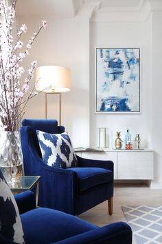 a living room filled with furniture and a blue chair next to a vase full of flowers