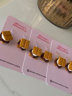 three pieces of food are on top of a pink card with silver earwires