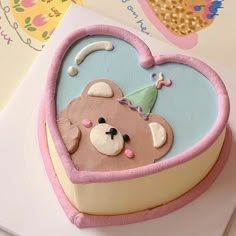 a cake shaped like a heart with a teddy bear in it's center, on top of a card