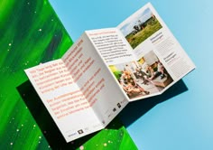 an open brochure on top of a green and blue background with white dots