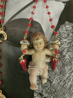 an angel figurine hanging from a chain with red beads and chains around it