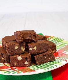 chocolate brownies stacked on top of each other on a plate with green and red table cloth