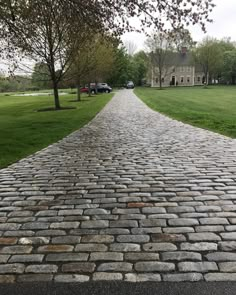 a cobblestone road in front of a large house