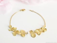 This elegant orchid bracelet is made of:- matte gold orchids;- Swarovski white crystal pearl;- gold plated chain with lobster clasp closure.All components are gold plated over brass.This listing is for bracelet only. See more orchid jewelry in my shop.Matching earrings:https://www.etsy.com/listing/486542466/gold-orchid-earrings-long-dangle-pearl Matching necklace:https://www.etsy.com/listing/500038915/gold-orchid-necklace-pearl-bridalIf you have any questions please send a message and I will be Gold Flower Bracelets For Wedding, Gold Pearl Flower Bracelets, Gold Flower Pearl Bracelet For Wedding, Elegant Matte Gold Wedding Jewelry, Dainty Gold Flower Pearl Bracelet, Delicate Flower-shaped Pearl Bracelet For Wedding, Delicate Floral Pearl Bracelet For Wedding, Dainty Gold Pearl Bracelet For Wedding, Dainty Gold-plated Pearl Bracelet For Wedding