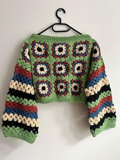 a crocheted sweater hanging on a hanger