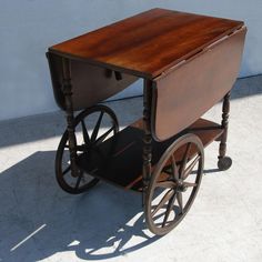 an old fashioned wooden cart with wheels on the front and back sides, against a white wall