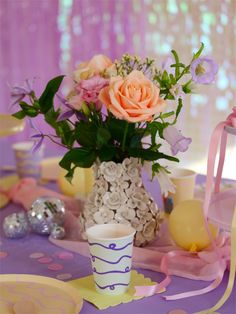 a vase filled with flowers sitting on top of a table next to confetti