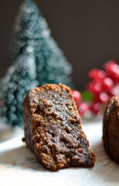 two pieces of chocolate cake sitting next to each other on a white plate with christmas trees in the background