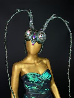 a mannequin dressed in green and blue with large horns on her head, wearing an elaborate costume