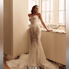 a woman in a wedding dress leaning on a window sill with her hand on her hip