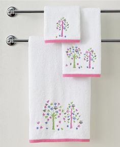 two white towels hanging on a towel rack with pink trimmings and embroidered trees