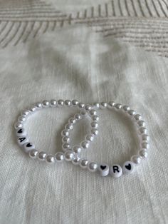 two bracelets that say love and are made out of pearls with black letters on them