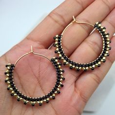 Elegant and unique dangle earrings in gold and black colours. Gold and black handwoven Miyuki beads on a gold plated hoop.  These can also be made in silver instead of gold, choose the option in the drop down menu.  The size of each hoop is approx. 3.8cm All jewellery comes gift wrapped and in black velvet drawstring bags, whether it is for a loved one or a treat for yourself. If you would like to include a hand written message just include a note in your order. Jewellery will be posted with tracking the next business day after placing order. Please note colours may vary slightly due to viewing device or monitor. *CARE TIPS* Take your jewellery off if you are involved in any activity which could scratch, knock or damage it. If in any doubt, take it off and keep it safe. Keep it well away f Bohemian Gold Beaded Circle Earrings, Black Dangle Jewelry With Gold Beads, Gold Bohemian Jewelry With Black Beads, Bohemian Gold Jewelry With Black Beads, Handmade Round Metal Beaded Earrings, Black Metal Round Beads Earrings, Black Metal Earrings With Round Beads, Handmade Black Circular Jewelry, Minimalist Handmade Black Hoop Earrings