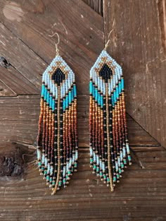 a pair of beaded earrings on top of a wooden table