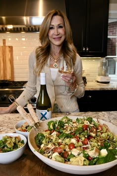 a woman standing in front of a salad and wine