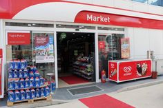 a market with many items on display in front of the storefront and red carpeted flooring