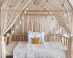 a canopy bed with white curtains and pillows