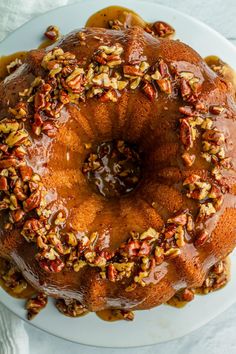 a bundt cake with pecans and caramel toppings on a white plate