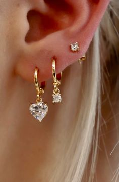 This CZ Heart Huggie ﻿is a fun yet sophisticated earring. These would look darling alone or stack with some of our studs to create a shiny layered look. Materials: Cz heart charm, gold plate brass huggies SKU: E1545G Three Hoop Ear Piercings, Double Earring Stack, Gold Heart Cartilage Earrings For Everyday, Everyday Gold Heart Cartilage Earrings, Gold Heart-shaped Cartilage Earrings, Gold Plated Huggie Earrings With Heart Charm, Dainty Huggie Earrings With Heart Charm, Gold Dainty Heart Earrings With Cubic Zirconia, Gold Cubic Zirconia Heart Earrings In Dainty Style