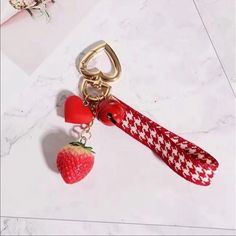 a strawberry shaped keychain with a red and white checkered ribbon attached to it