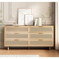 a wooden dresser sitting in front of a wall with pictures and plants on top of it