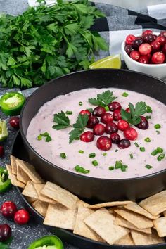 a bowl of dip with cranberries and cilantro on the side