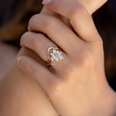 a woman's hand with a flower ring on her left hand and a diamond in the middle