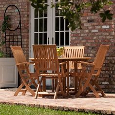 a wooden table and chairs sitting on top of a stone patio next to a brick building