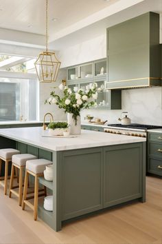 a large kitchen with green cabinets and white counter tops, an island in the middle