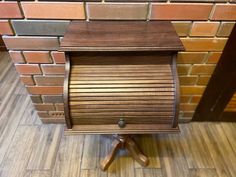 an old fashioned wooden mailbox sitting on top of a wood floor next to a brick wall