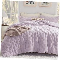 a bed covered in a purple blanket and pillows