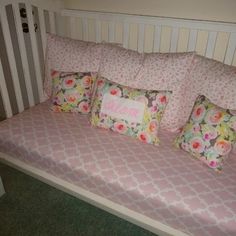 a white crib with pink bedding and pillows