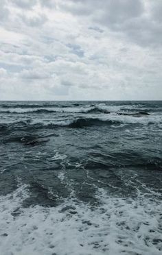 the ocean is very choppy and dark with some waves coming in to shore on an overcast day