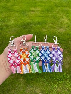 a person is holding six different colored key chains in their hand, with one being held by the other