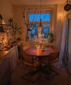 a dining room table with candles on it in front of a window and potted plants