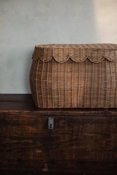 a wicker basket sitting on top of a wooden table next to a wall and door