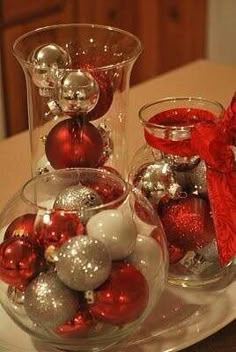 two glass vases filled with ornaments on top of a white table next to a red bow