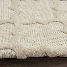 a close up view of a white rug on a wooden floor with dark wood floors