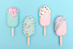 four ice cream lollipops with sprinkles on them are lined up against a blue background