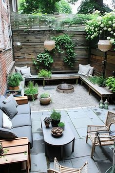 an outdoor living area with couches, tables and plants on the side of it