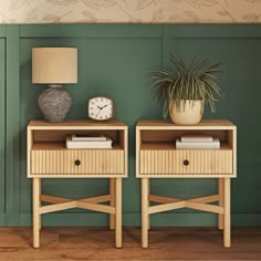 two wooden nightstands with plants and a clock on each side, against a green wall