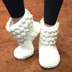 someone is wearing white crocheted boots with black leggings on the floor