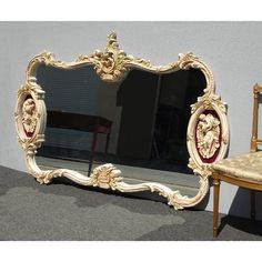 an ornately decorated mirror sitting next to a wooden chair on top of a carpeted floor