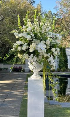 a white vase filled with lots of flowers on top of a table next to a pool