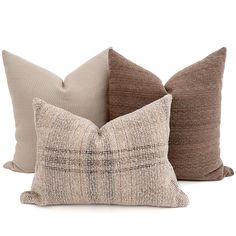 three pillows with different colors and patterns on the front, one in beige and one in brown